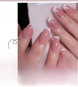 Close-up of white French tip press-on nails with small rhinestones and pink base