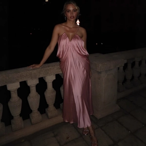 Detail of pink silk evening dress with elegant V-neck and satin drapes in night setting