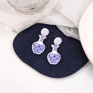 Detail of blue and white porcelain style earrings on a textured blue display mat