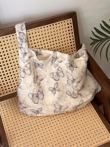 Chic butterfly print lace tote bag with textured feather fabric on a vintage wooden chair