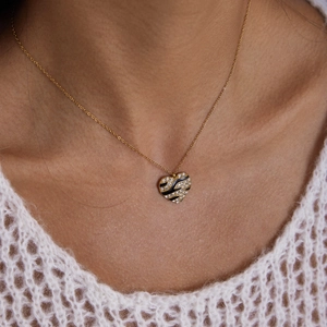 Close-up of golden heart pendant with zebra patterns and crystals worn on model