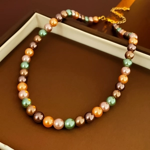 Vue macro d'un bracelet de perles multicolores avec fermoir doré sur écrin à bijoux marron
