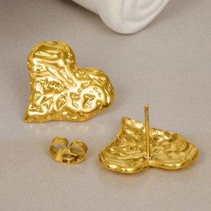 Irregular hammered heart-shaped gold stud earrings with textured metallic finish