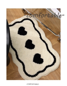 Close-up of heart pattern bath mat with thick tufted texture and wavy black edges