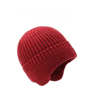 Detail of dark red thick knit winter hat with ear flaps and vertical ribbed texture