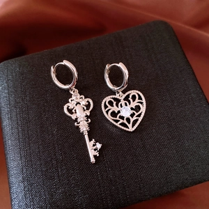 Detail of silver heart and key earrings with white zircons on black jewelry box
