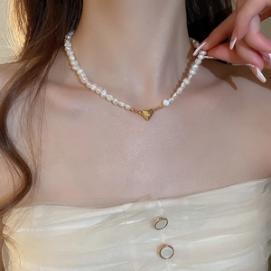 Detail of 18K gold heart pendant and natural freshwater pearls on a model neck