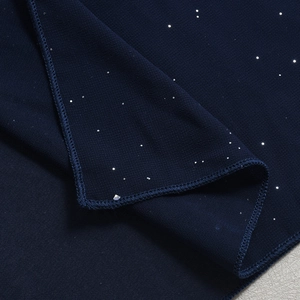 Detail von dunkelblauem Stoff mit silbernen Glitzerpunkten und feiner Nahtkante