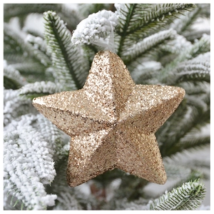 Close-up of a sparkling gold glitter star ornament hanging on a snowy Christmas tree branch
