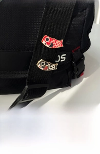 Detailed view of red and black koi fish enamel pins attached to a black canvas strap