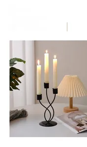 Detailed close-up of a black three-arm iron candle holder with sleek curved base design