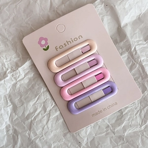 Set of four pastel pink and purple oval hair clips displayed on a card holder