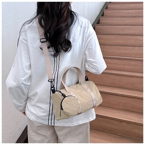 Detail of beige nylon boston bag with mini round pouch shown on a person’s back