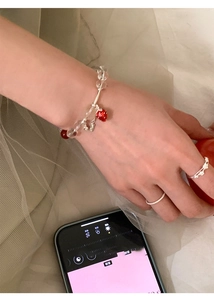 Detail showing beaded bracelet with red strawberry pendant and silver tubes on model's wrist