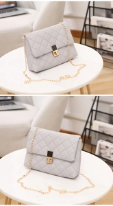 Macro shot of light gray quilted leather bag showing golden chain and square metal lock