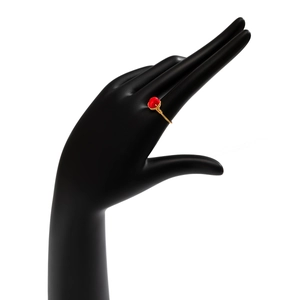 Detail of handmade gold wire-wrapped ring with irregular red stone on black display