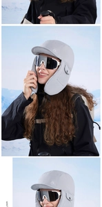 Detail of grey winter earflap hat with brim and goggles for outdoor skiing in snow