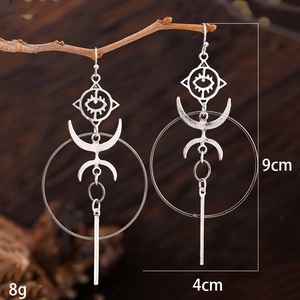 Bohemian antique silver earrings with eye and moon motifs hanging on a branch