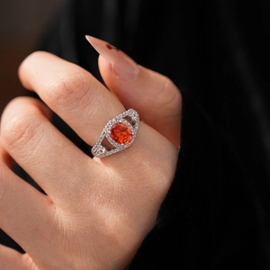 Macro shot of oval orange gemstone ring with silver band and brilliant diamond halo