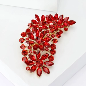 Detail of vintage style brooch with red rhinestones and golden floral alloy base