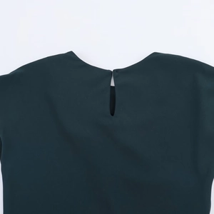 Dettaglio di un abito verde scuro con apertura a goccia sulla schiena e chiusura a bottone