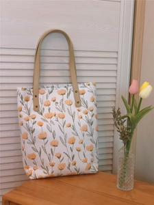 Détail du sac cabas en toile à fleurs avec anses en cuir et motif floral orange