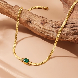 Detail of vintage gold snake chain necklace with emerald stone and cubic zirconia accents