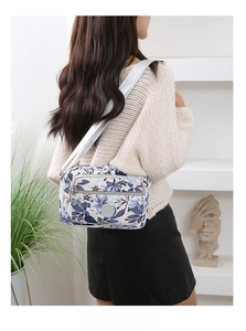 Close-up of a blue floral crossbody bag with multiple zip pockets and adjustable strap