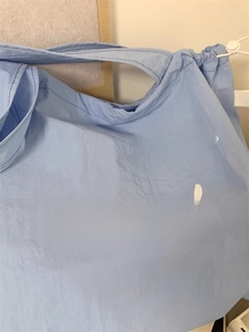 Detail of light blue drawstring tote bag showing white Wdbild lettering and fabric texture
