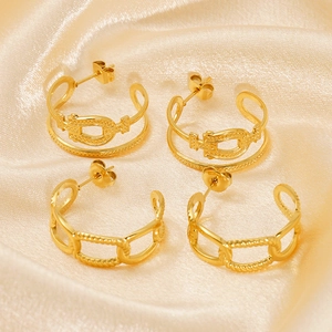 Detail of two pairs of gold C-shaped earrings with chain and bead textures on silk