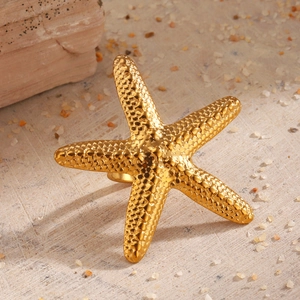 Golden oversized starfish open ring with realistic bionic texture on sand beach background