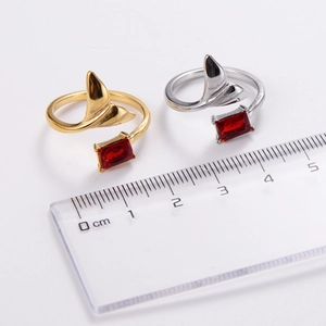 Detail of adjustable fishtail rings with red zircon stone measured with a ruler