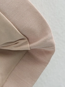 Detailed close-up showing the fine knitted fabric texture of a beige sleeveless dress