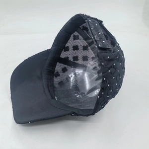 Detail view of black baseball cap showing dot pattern and adjustable strap closure