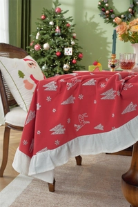 Detail of red Christmas tablecloth featuring white reindeer patterns and ruffled edges