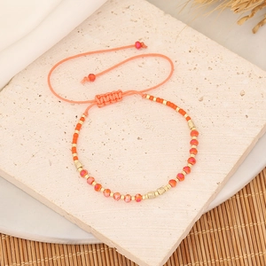 Detail of hand-woven beaded bracelet with orange crystals and adjustable gold beads