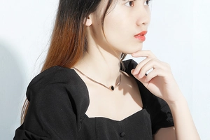 Close-up of gold flat snake chain necklace with a black round shell pendant on neck