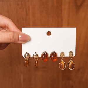 Three-piece retro resin earring set featuring golden metal and amber teardrop pendants