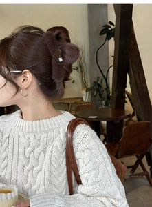 Detail of plush brown claw clip with leopard heart and crystal worn on a hair bun