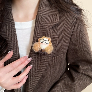Detailed view of a handmade flocked teddy bear brooch worn on a dark brown suit blazer
