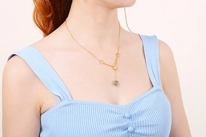 Detailed view of a gold heart necklace featuring black and white gemstone pendants on a model