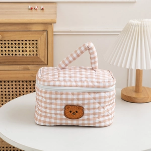 Detail of the quilted cotton gingham makeup bag with a cute brown bear embroidery