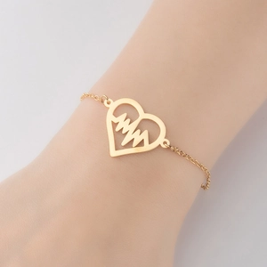 Detail of adjustable gold heartbeat heart charm bracelet on a woman wrist