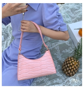 Pink crocodile pattern shoulder bag shown in a soft outdoor lifestyle picnic setting