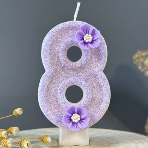 Sparkling purple number 8 birthday candle with 3D floral accents on a wooden base
