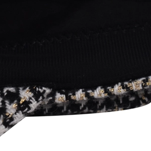 Macro view of black and white houndstooth fabric with gold metallic thread details