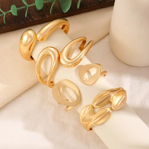 Detail view of stacked irregular gold alloy bangles on a cream display stand