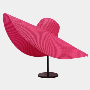 Macro detail of high-density rose pink woven straw on an oversized sun hat with wavy brim