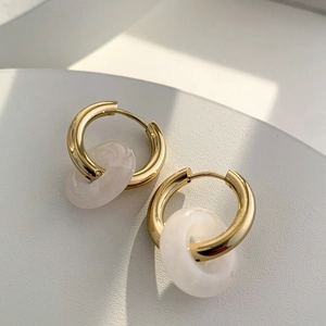 Detail of 18K gold hoop earrings featuring translucent white natural stone pendants