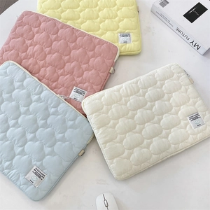 Detailed cloud-quilted laptop sleeve cases in soft pastel colors on a desktop setup